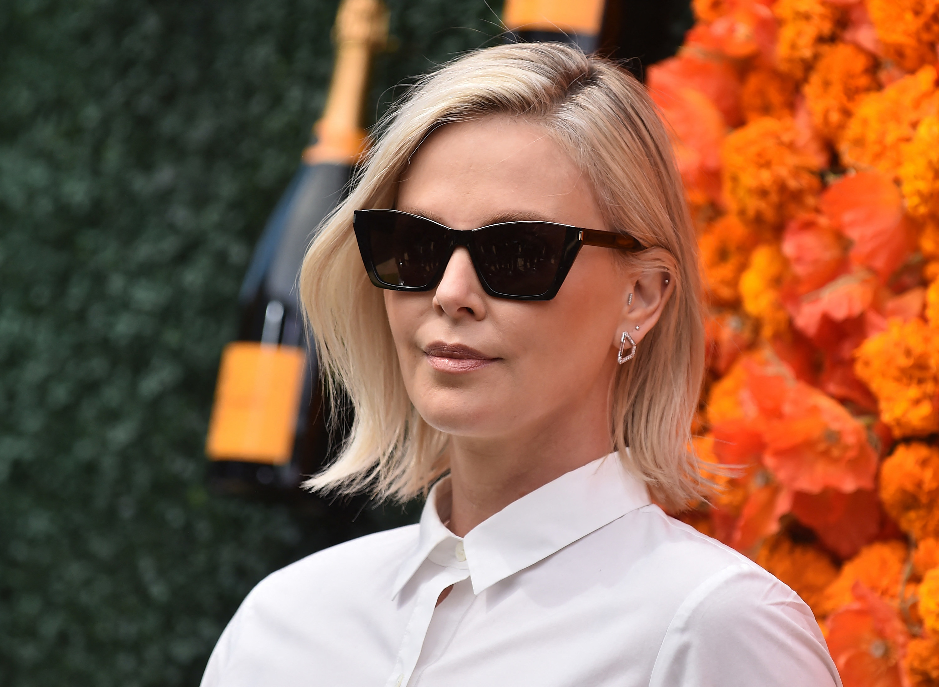 Charlize Theron wearing sunglasses with a straight face