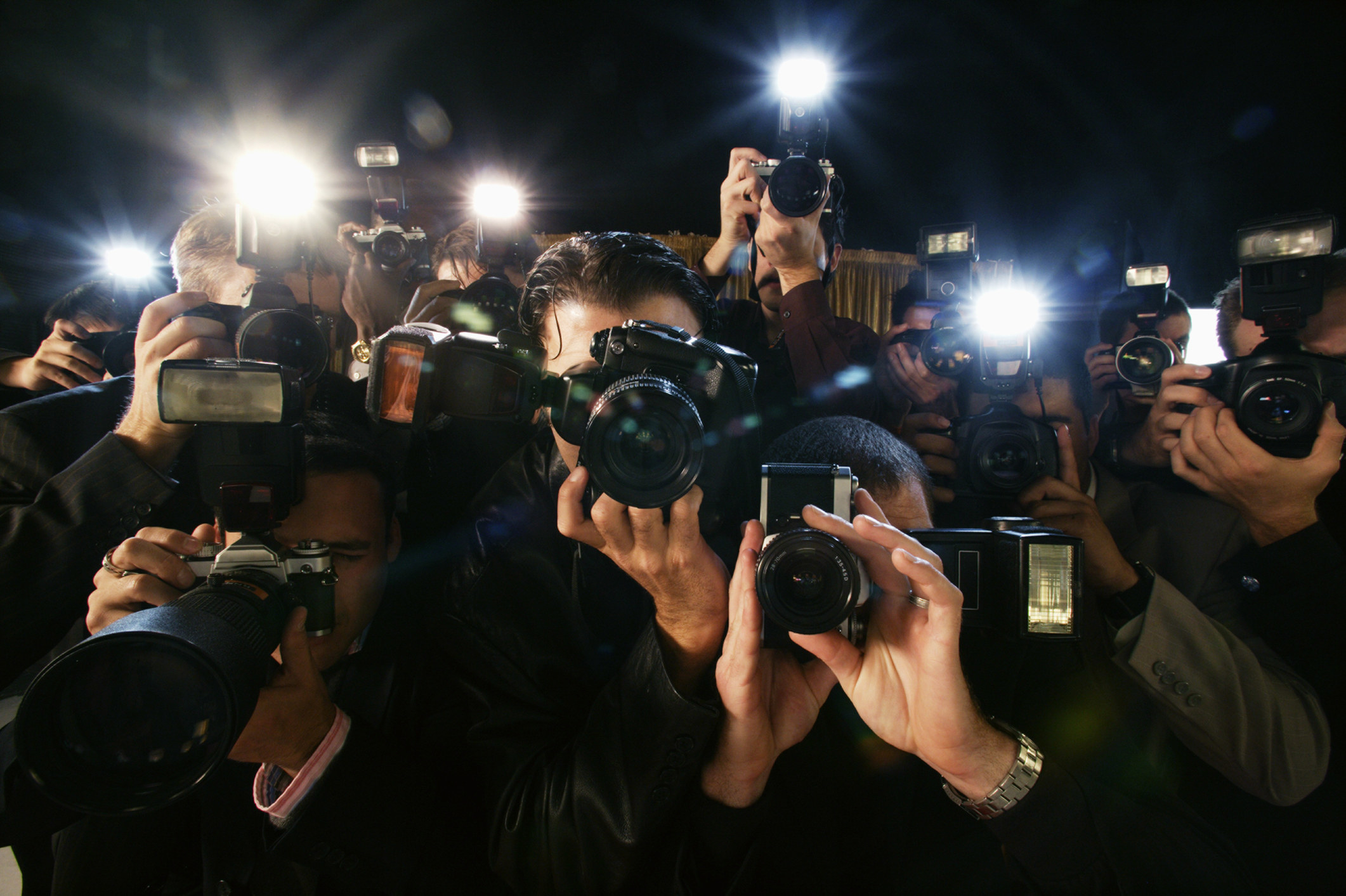 A crowd of paparazzi holding their cameras to their faces