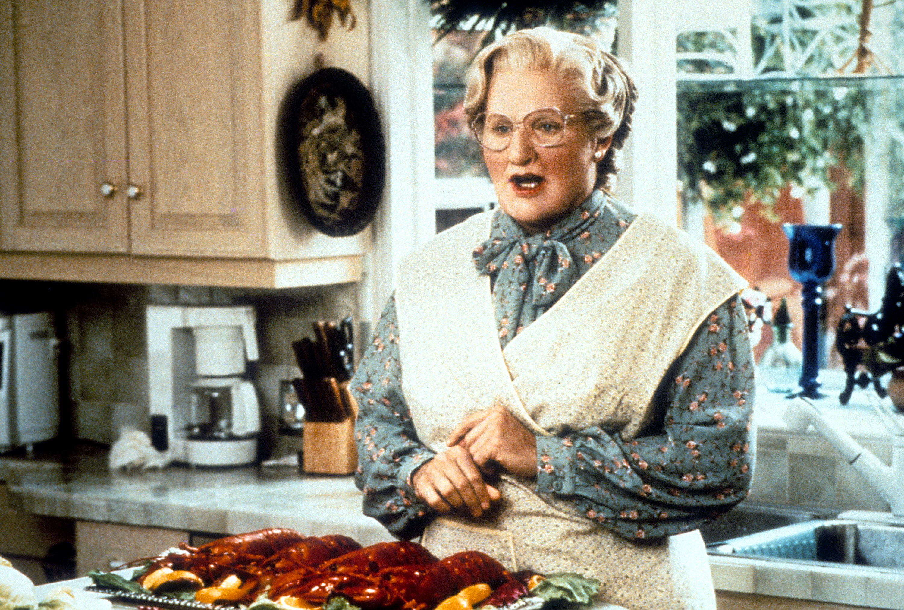 Robin Williams is stunned with his mouth open while performing as Mrs. Doubtfire in a kitchen scene
