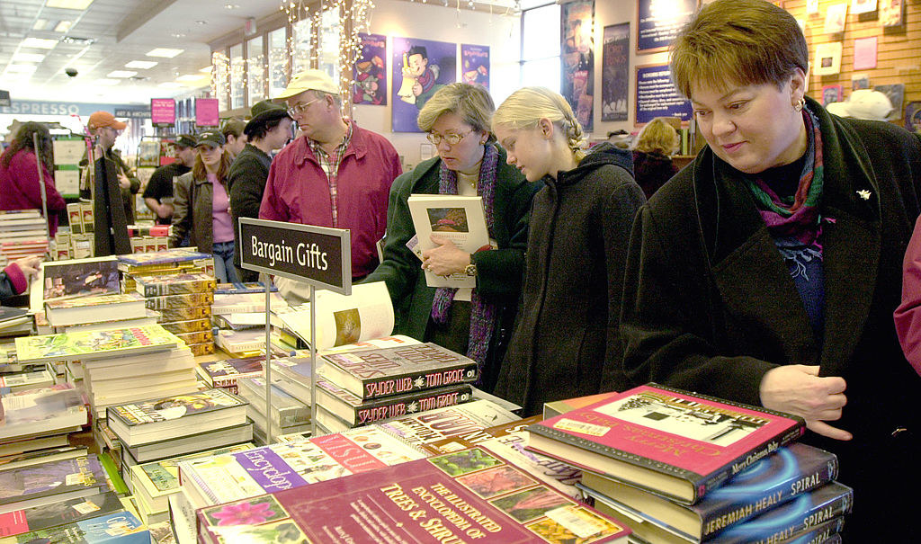 A crowded store with people looking over a crowded bargain books table