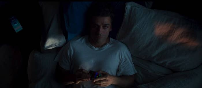 Marc Spector lays in bed with a Rubiks cube