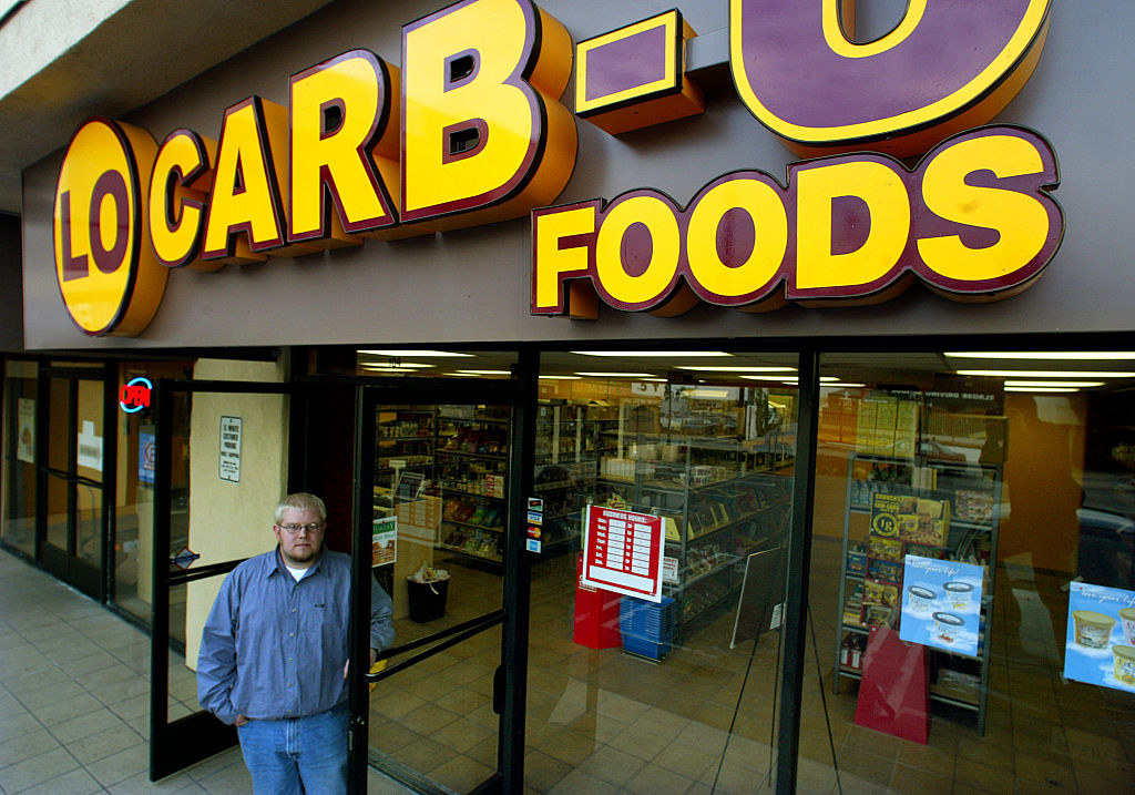 Man holding doors open to a store called Lo Carb-U foods