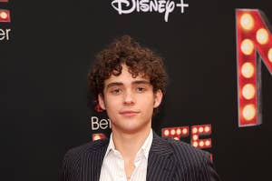 Joshua poses at a step-and-repeat with his hands in his pockets