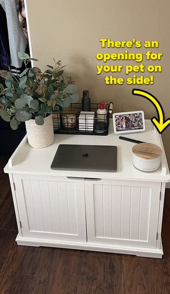the litter box enclosure in white, being used as a reviewer's nightstand with text that reads 