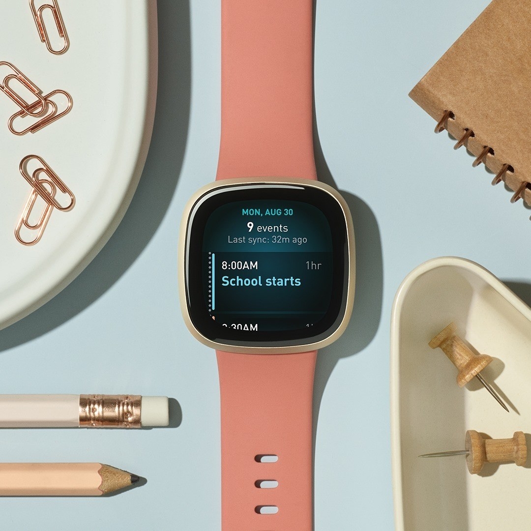 The FitBit next to a pencils, a notebook, and other office supplies