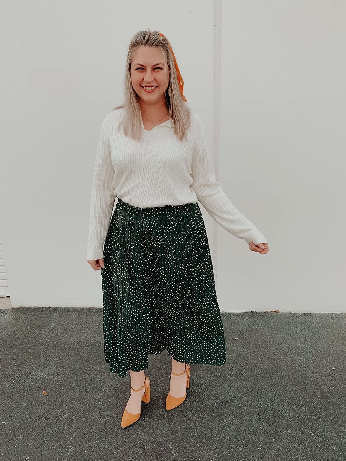 A reviewer wearing a black maxi skirt with white tiny specks throughout and white top