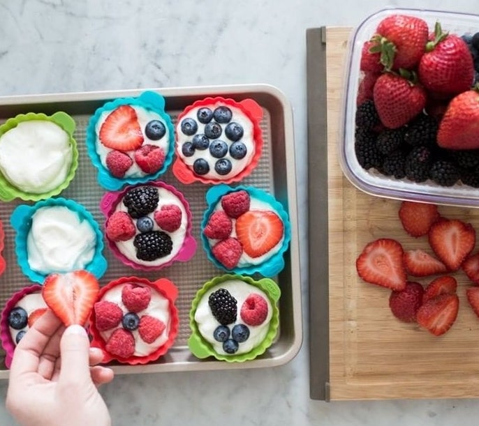 a top-down view of someone using the silicone muffin cups for fruit-topped desserts