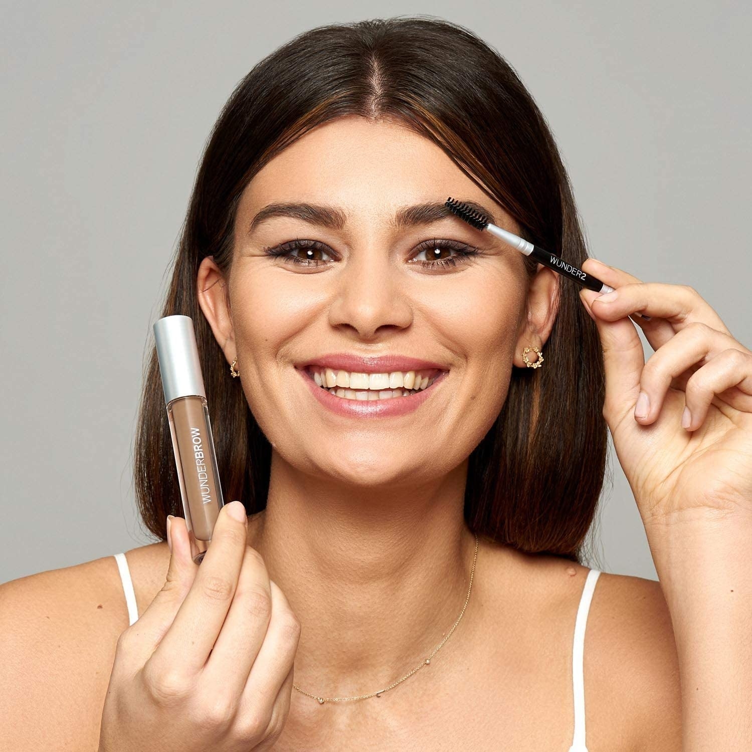 a smiling person using the brow gel on their eyebrows