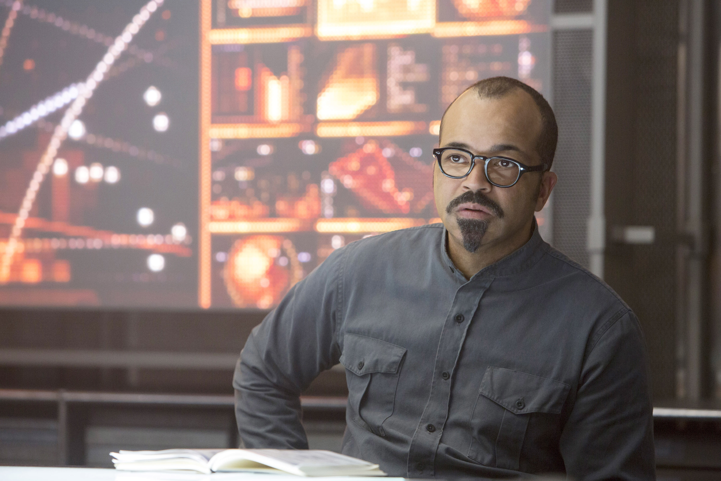 Jeffrey Wright as Beetee sits with a book open in front of him