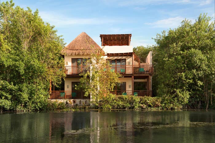 One of the hotel's buildings, set among trees alongside a river