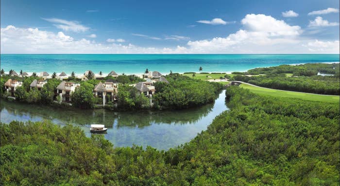 An aerial view of the resort, with a boat traveling along a river that is lined with casitas