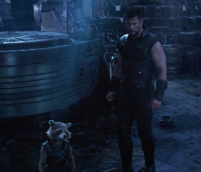 Thor and Rocket look for Stormbreaker in a dark workshop
