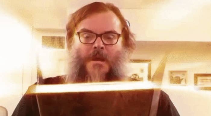 Jack Black opening a book that emits light in front of his face