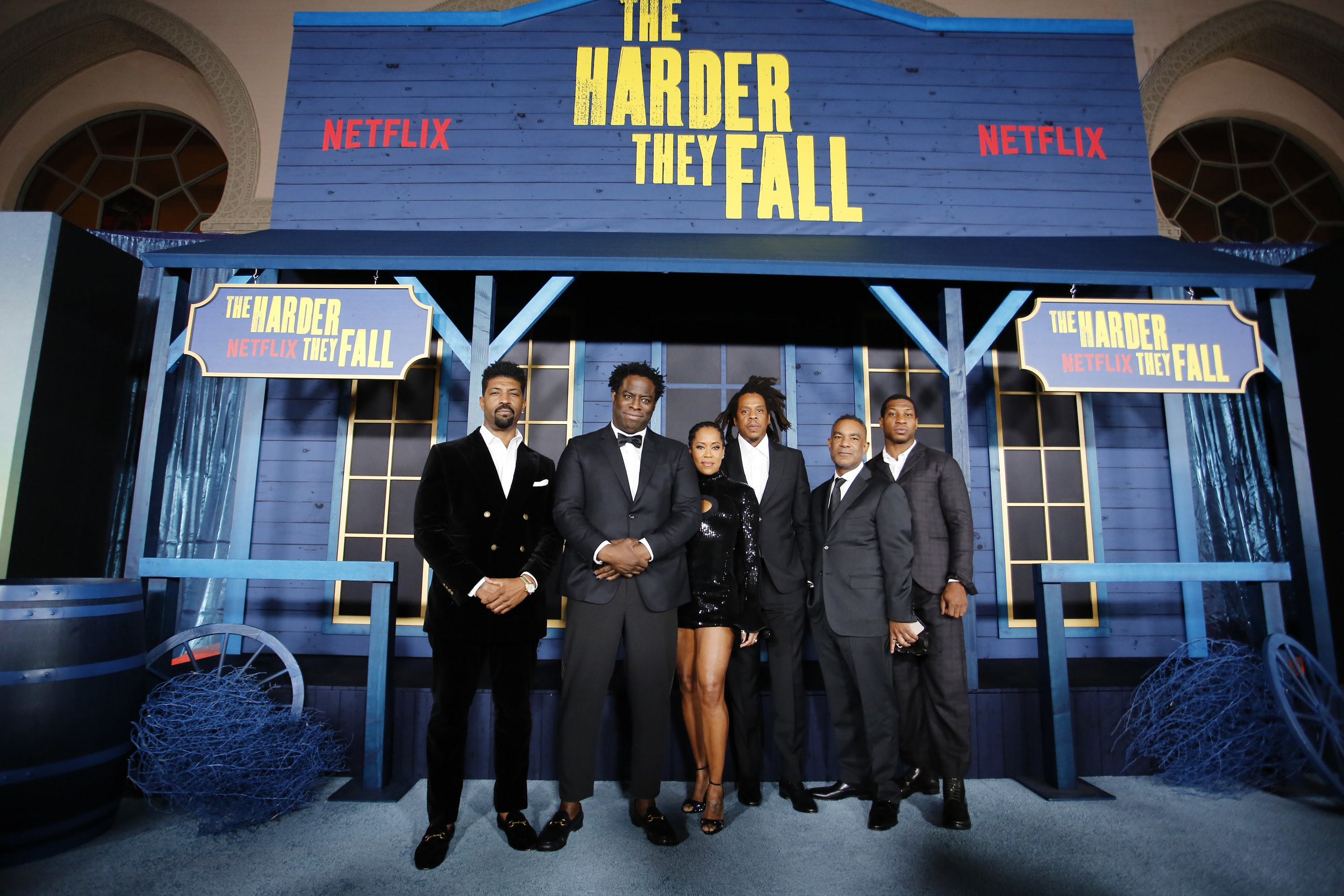&quot;The Harder They Fall&quot; cast and production members pose in front of a pop-up saloon at an event for the film