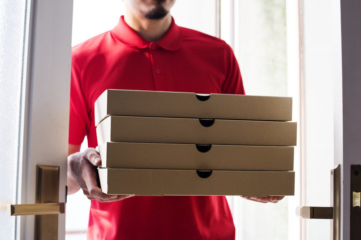 Pizza delivery person holding pizza boxes