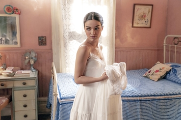 Rachel holds a white dress in her bedroom