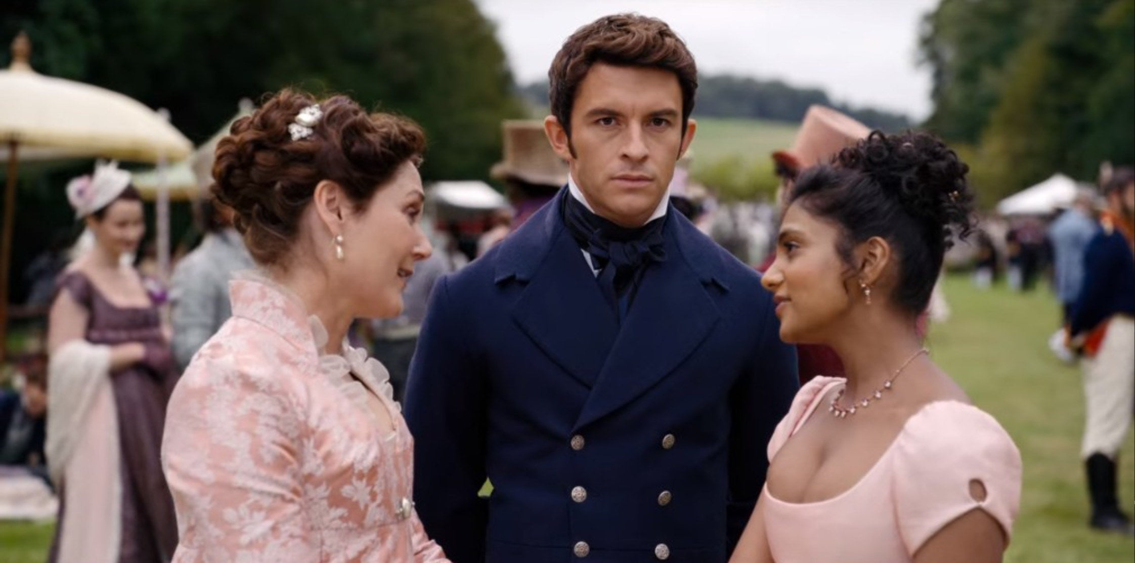 Anthony looking at Kate (off-screen) while standing with his mother, Violet Bridgerton, and Edwina Sharma.