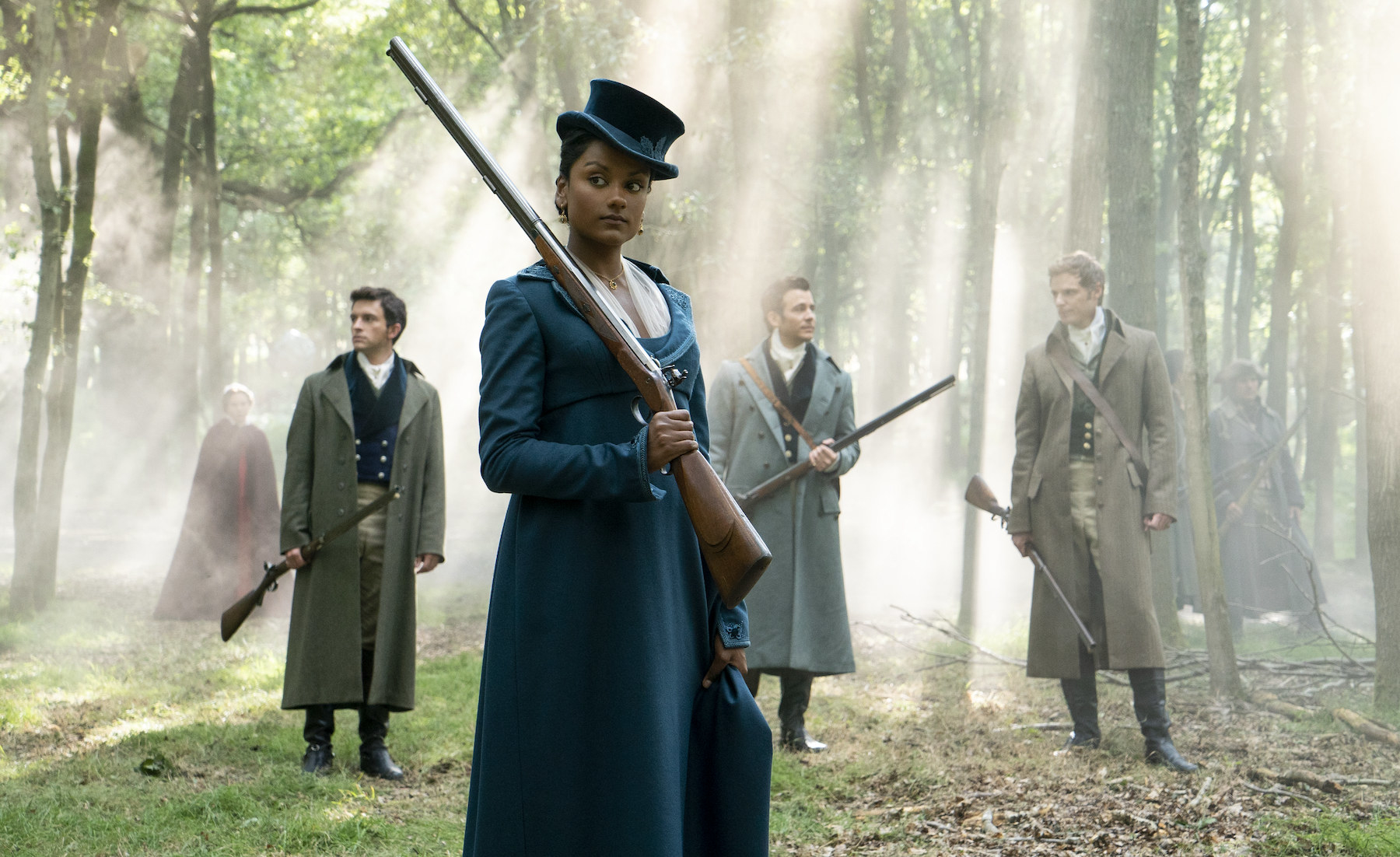 Kate with a rifle on her shoulder with men standing behind her