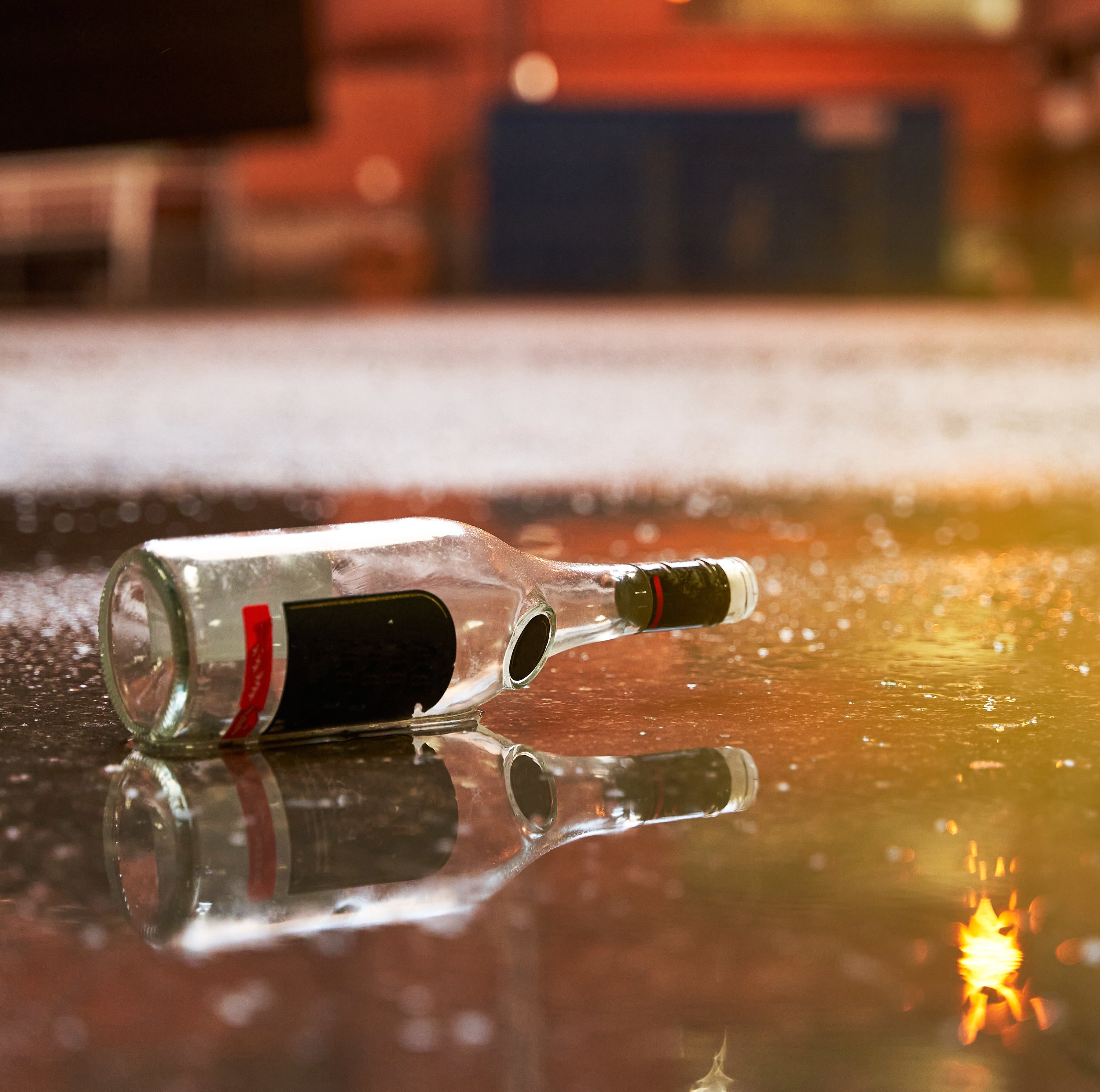 Garbage after-party in the street concept. Empty alcohol bottle on the floor at campus during sunset