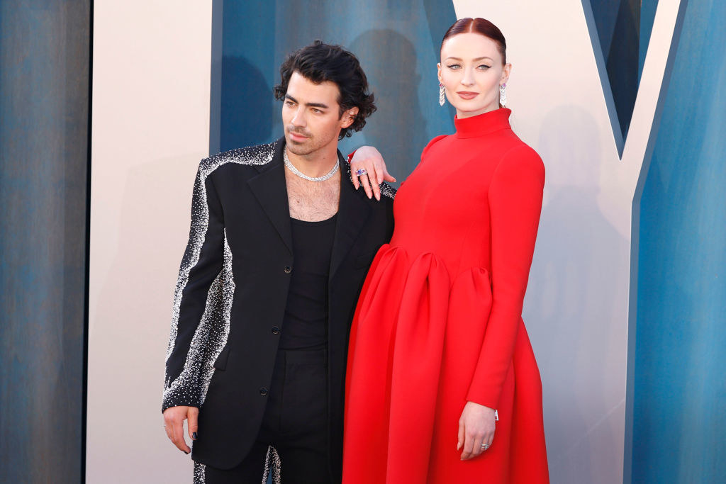 Joe in a suit standing with a pregnant Sophie