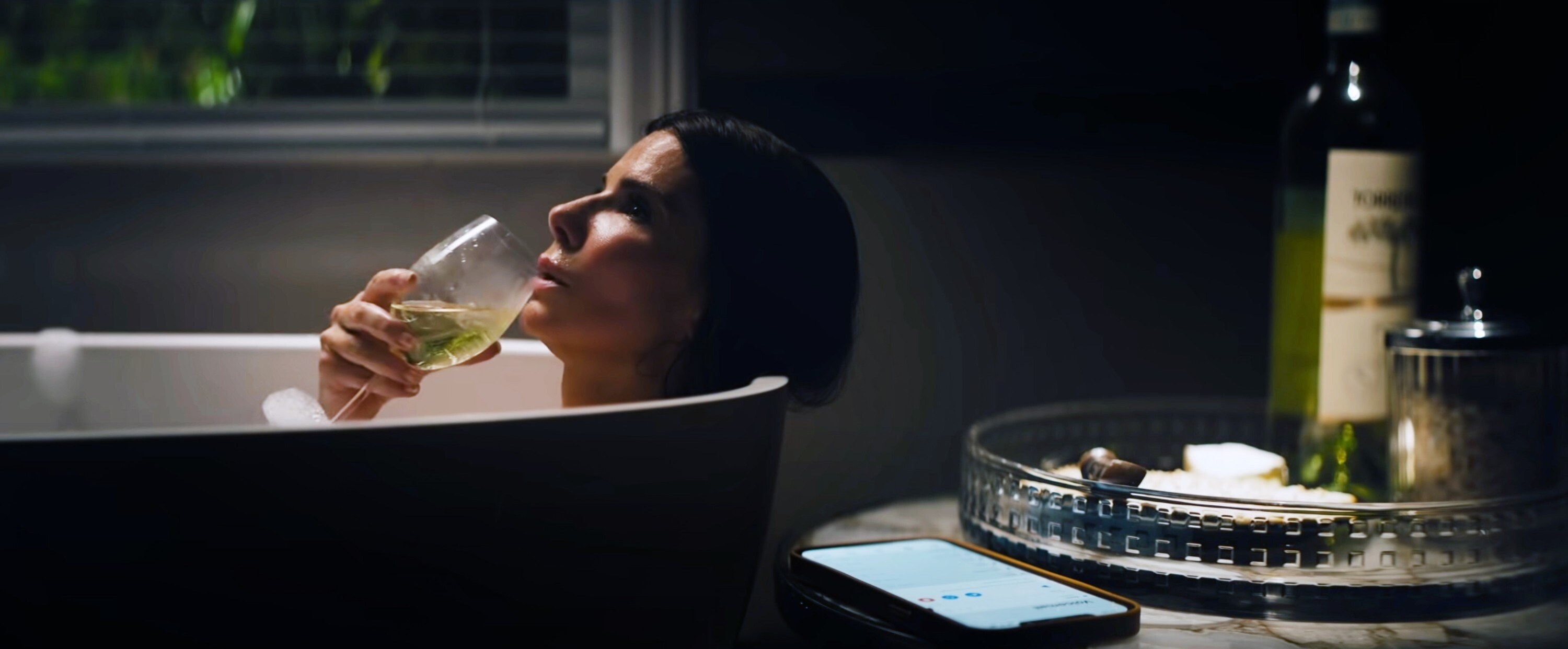 Sandra Bullock drinking wine in the bath in The Lost City