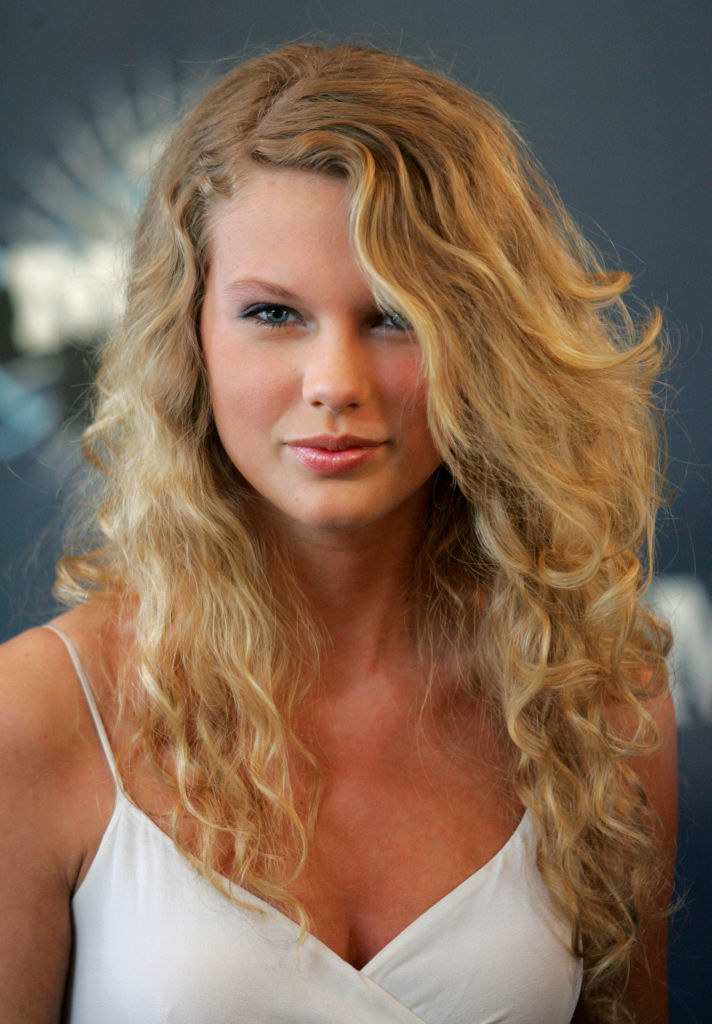 Close-up of Taylor smiling at the camera and wearing a spaghetti-strap top