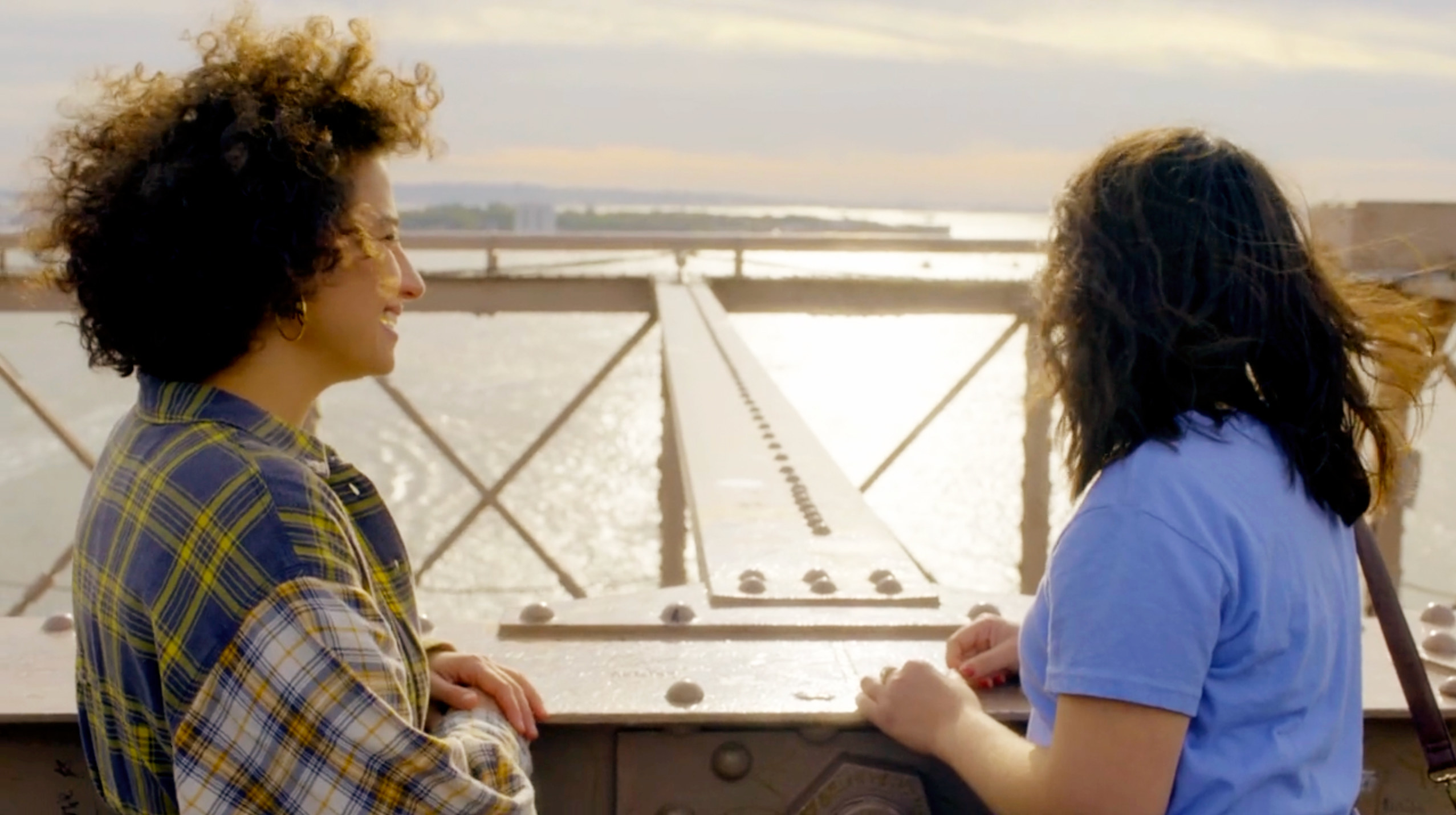 A screenshot from the show&#x27;s finale shows Ilana and Abby on the Brooklyn Bridge. Ilana is smiling with her hands folded on the side of the bridge, looking over at Abby, who is looking out at the water, her hair blowing in the wind behind her.