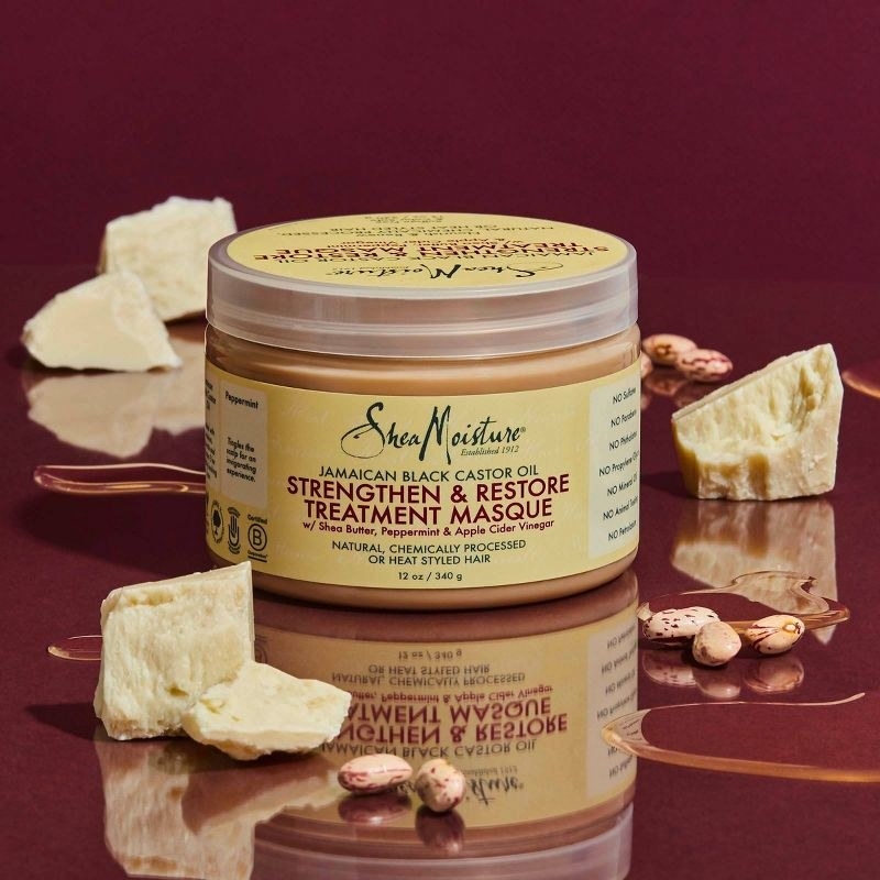 A jar of tan hair product with yellow red and green packaging with nuts and shea butter
