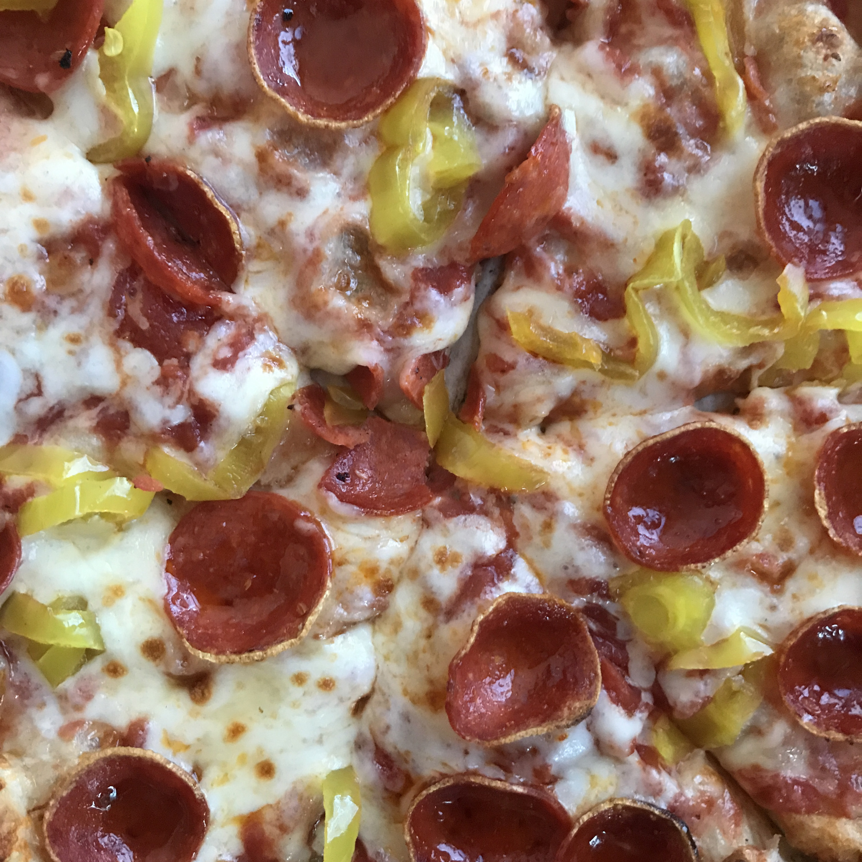 A pizza with pepperoni and banana peppers