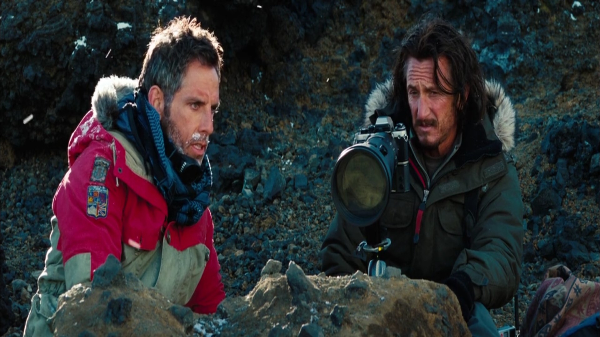 Ben Stiller on top of a mountain talks to Sean Penn who has a big camera in front of him