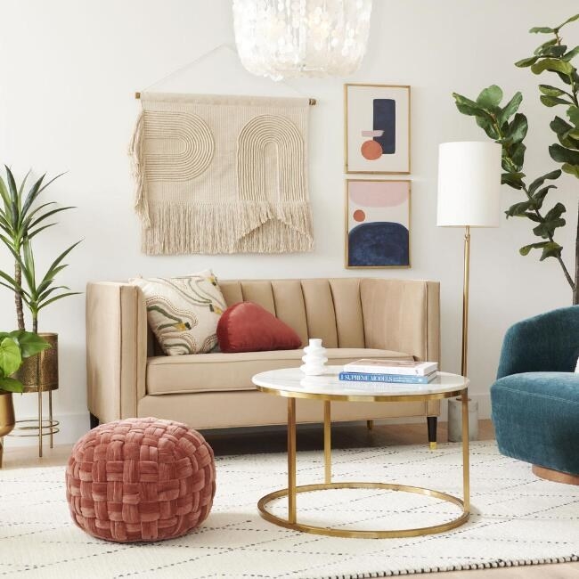 the beige velvety loveseat with pillows on it staged in a boho living room