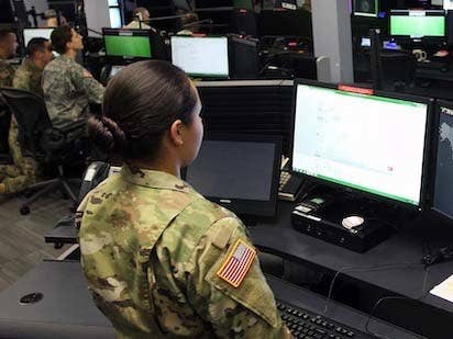 A person with an Army uniform looks at a computer monitor