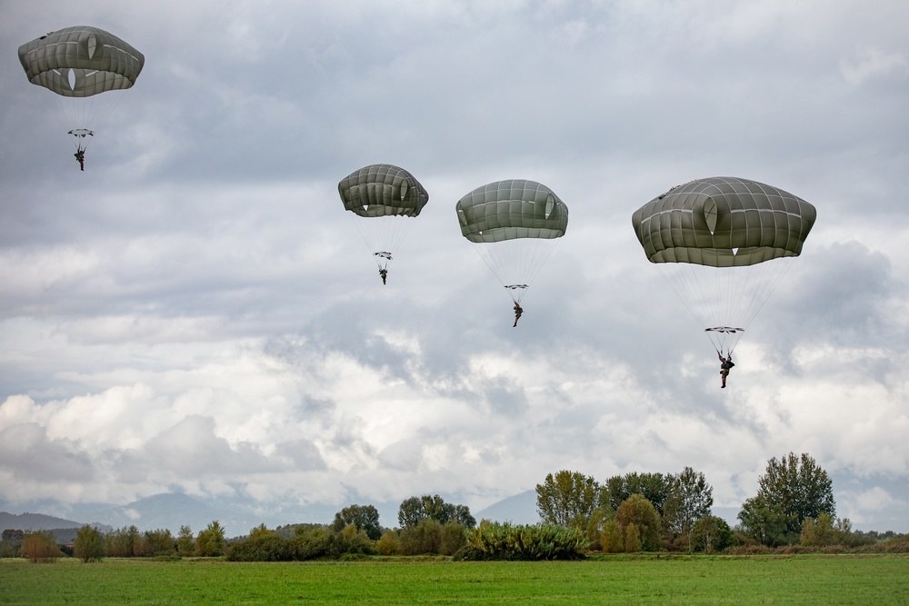 Four people descending from the sky with parachutes