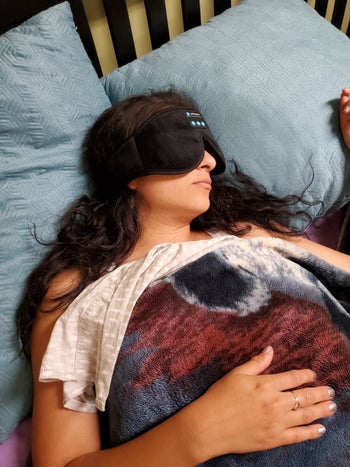 pic of reviewer wearing black Bluetooth-enabled mask over eyes while resting in bed