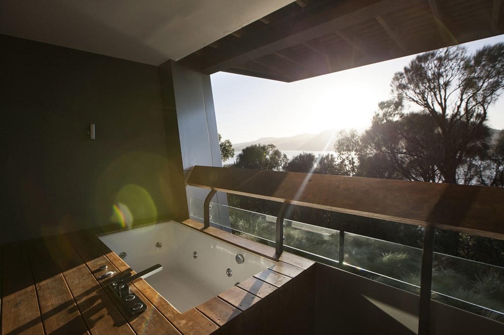 An outdoor jetted tub on a balcony overlooking the river in one of the hotel&#x27;s suites
