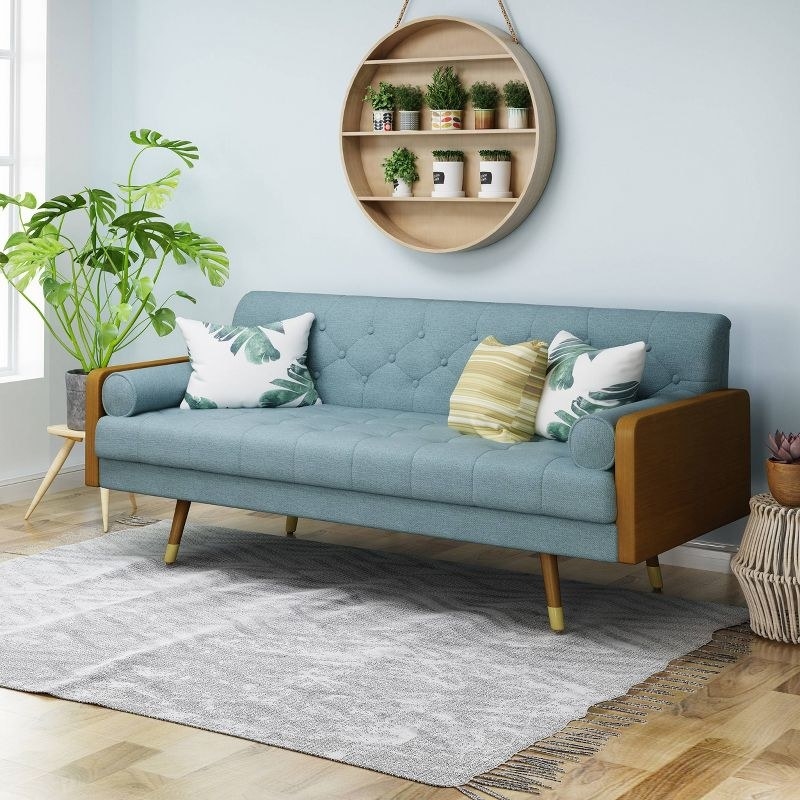 blue sofa with three pillows on it