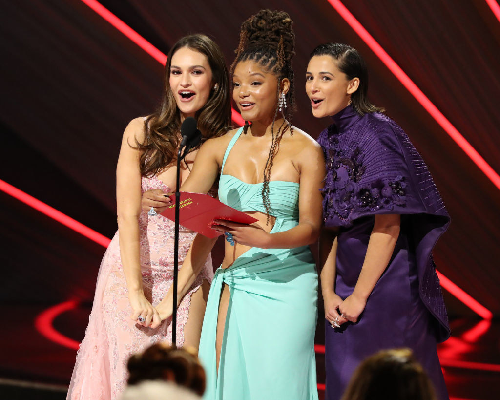 Lily James, Halle Bailey, and Naomi Scott standing close together at the podium