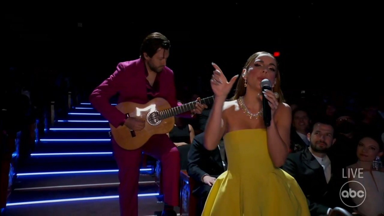 A guitarist accompanies a woman singing the song onstage