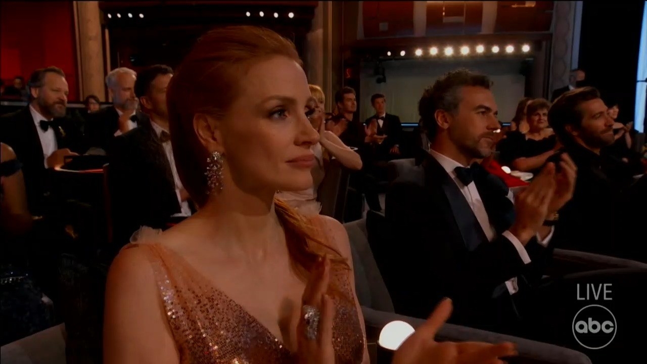 Jessica sitting in the audience clapping and looking unamused