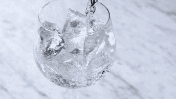 Water filling up a glass full of ice
