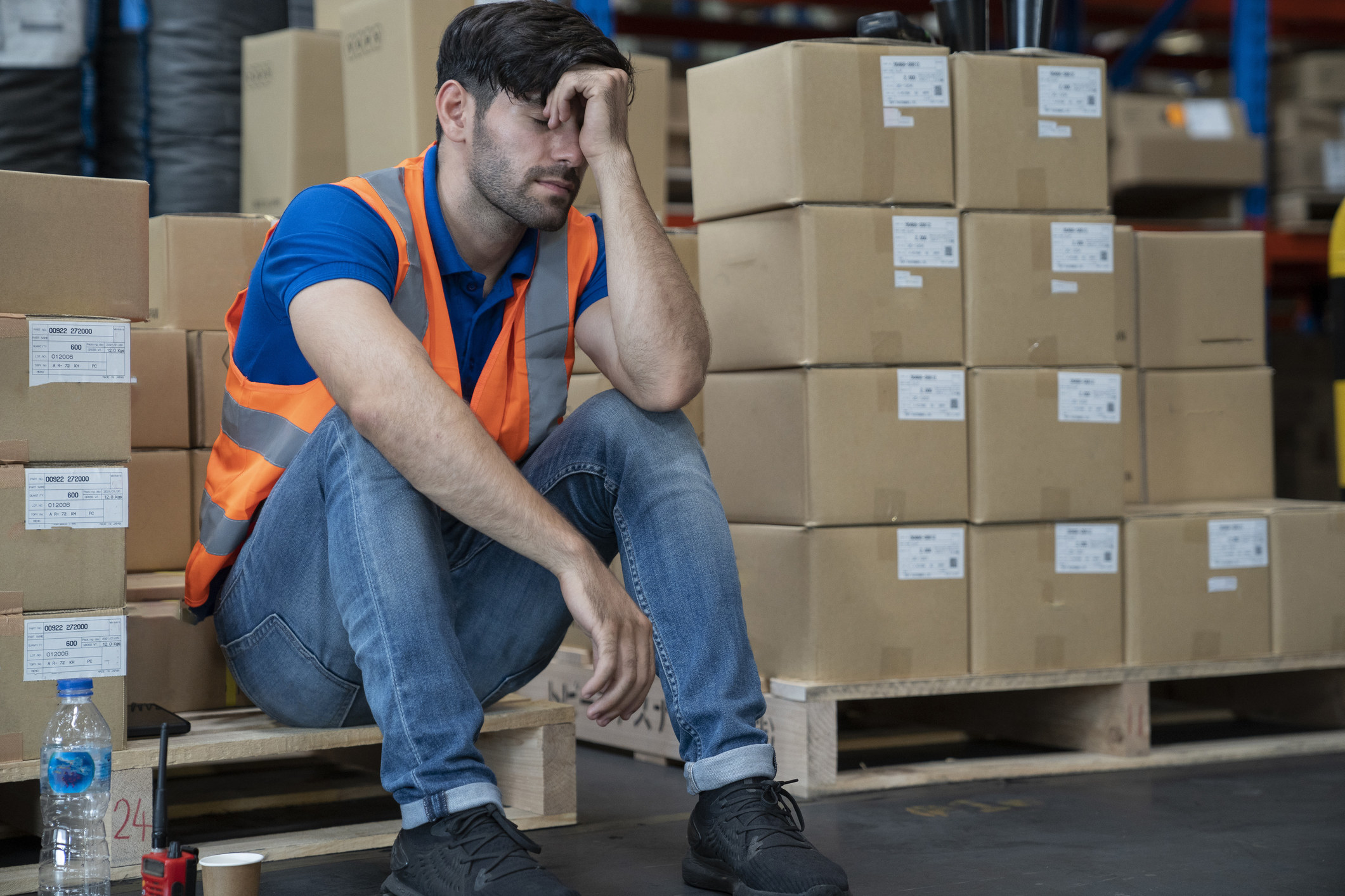 A man looks tired at work in front of piles of boxes