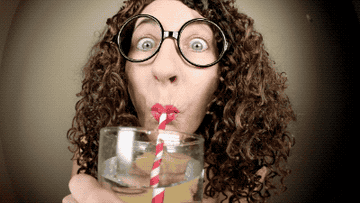 Woman looks at camera while drinking water with a straw
