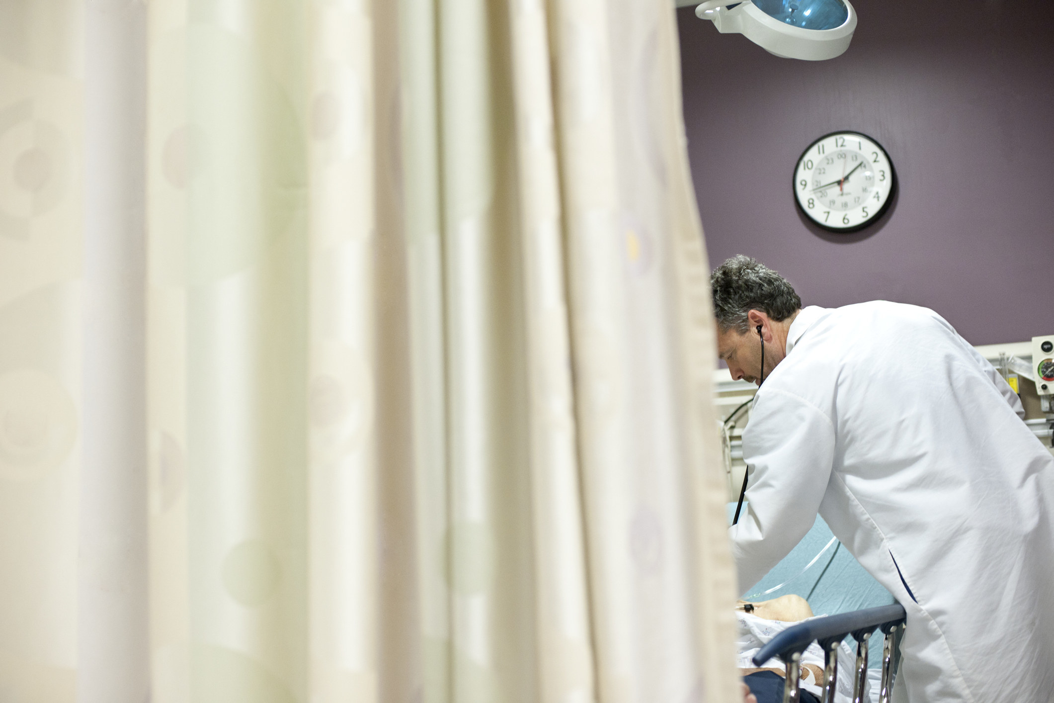 Doctor working behind a hospital curtain