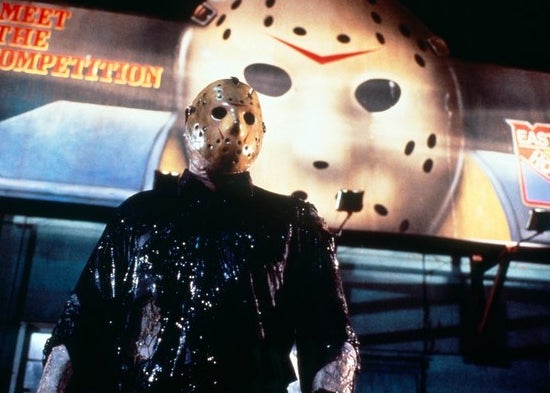 Jason Voorhees in front of a billboard with his mask on it