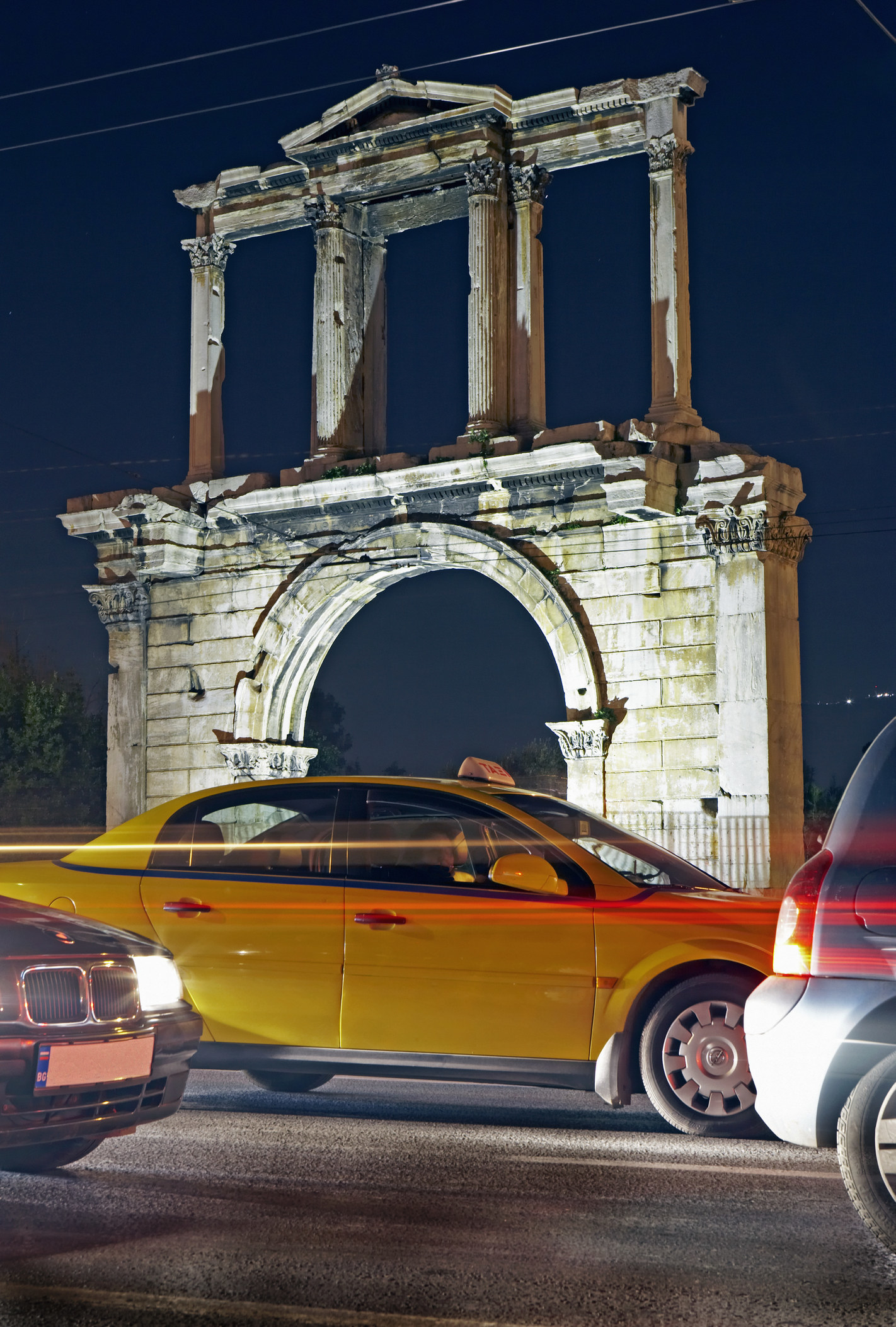 A taxi beneath an old structure in Athens.