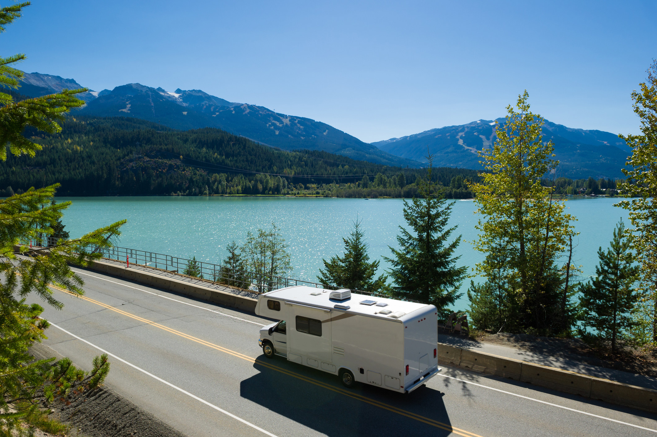 An RV driving on a road beside a lake