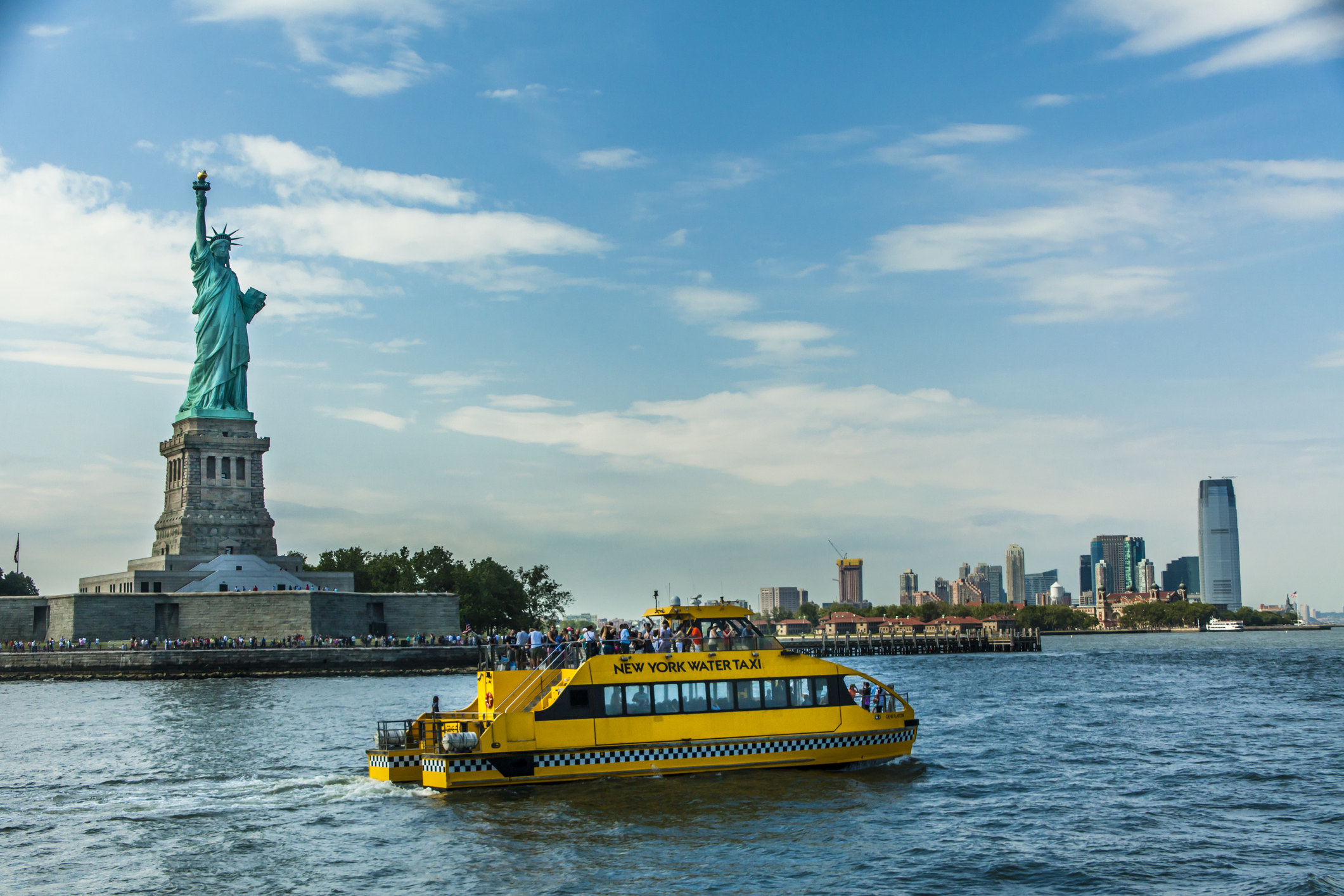 Statue of Liberty and Tour Boat and lower Manhattan.