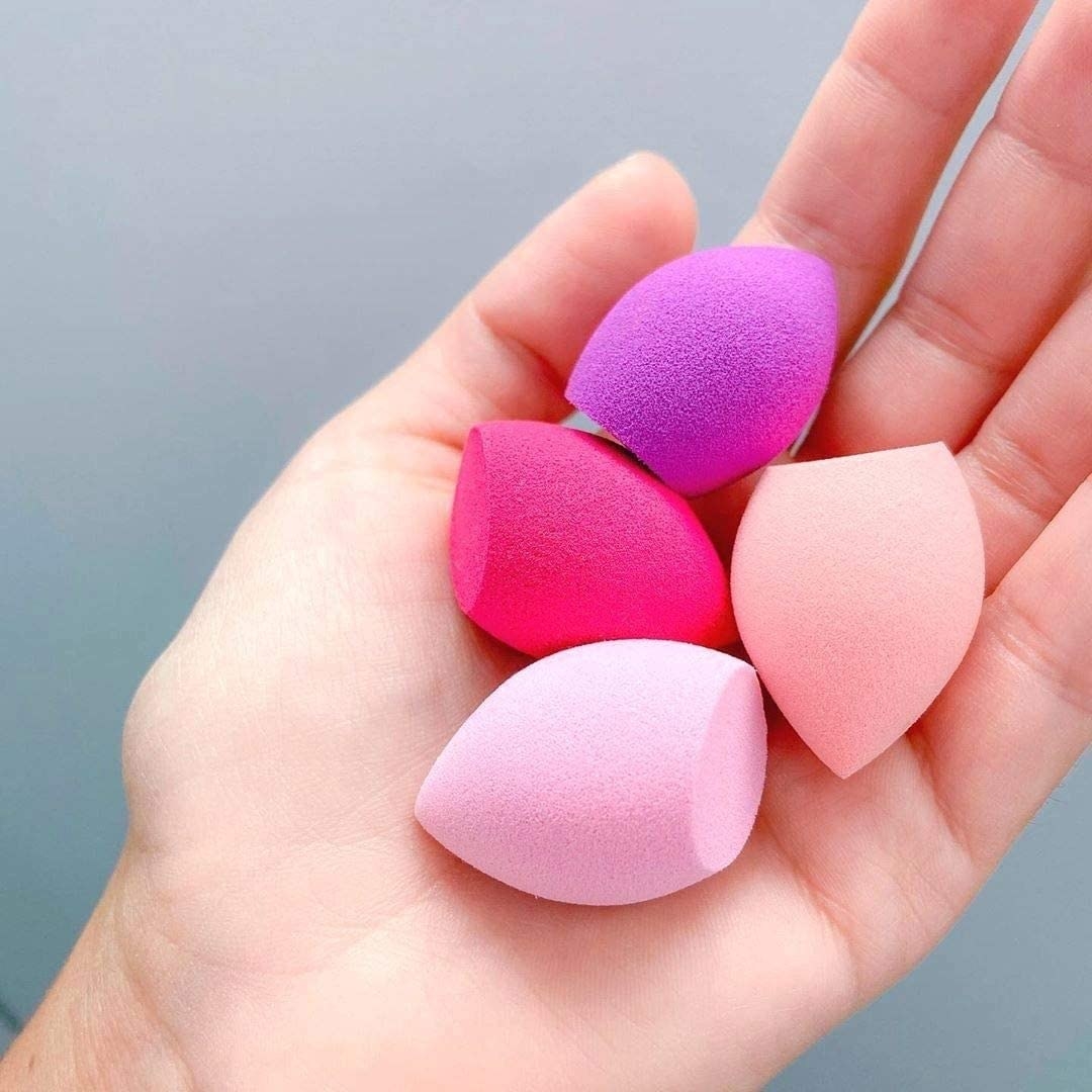 A person holding four beauty blenders in their hand