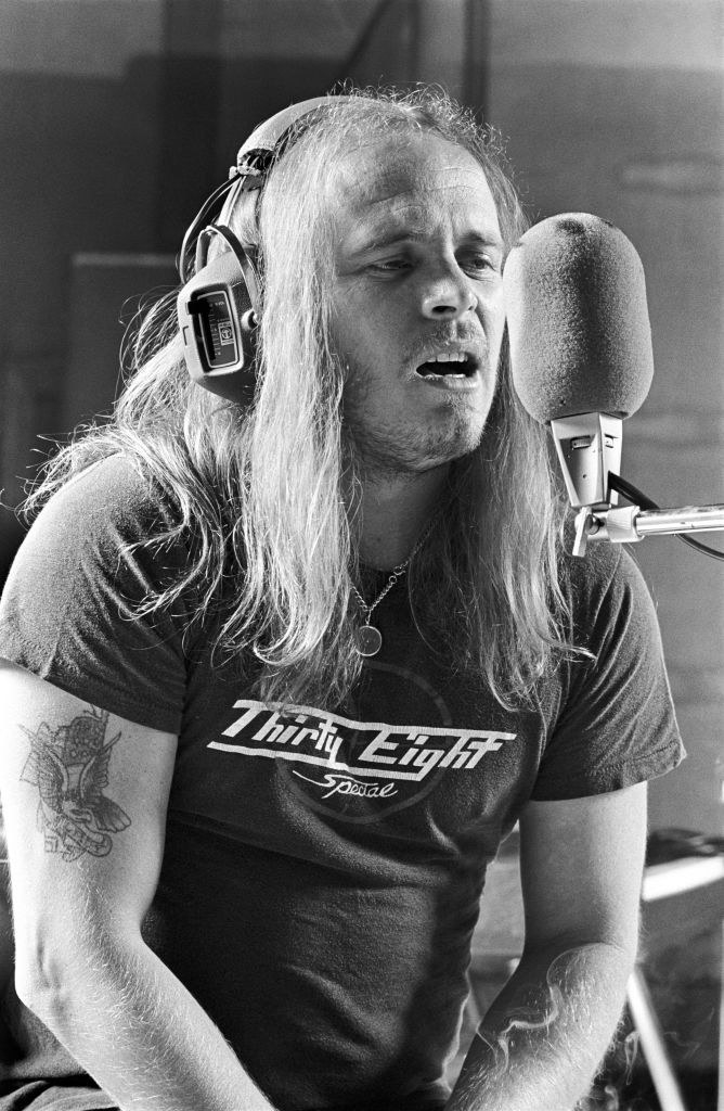 A black and white photo of a man with long hair and headphones singing