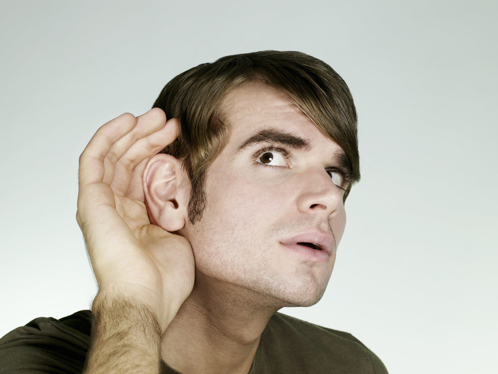 a man leaning in to hear better with his hand and ear enlarged for effect